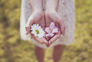 A person holding pink and white birth flowers on a green field.
