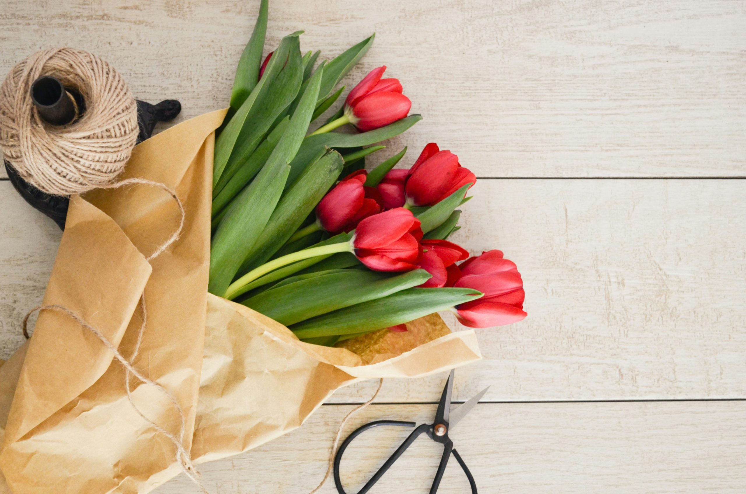 An image depicting sending flowers with packaging material on a brown wooden table.