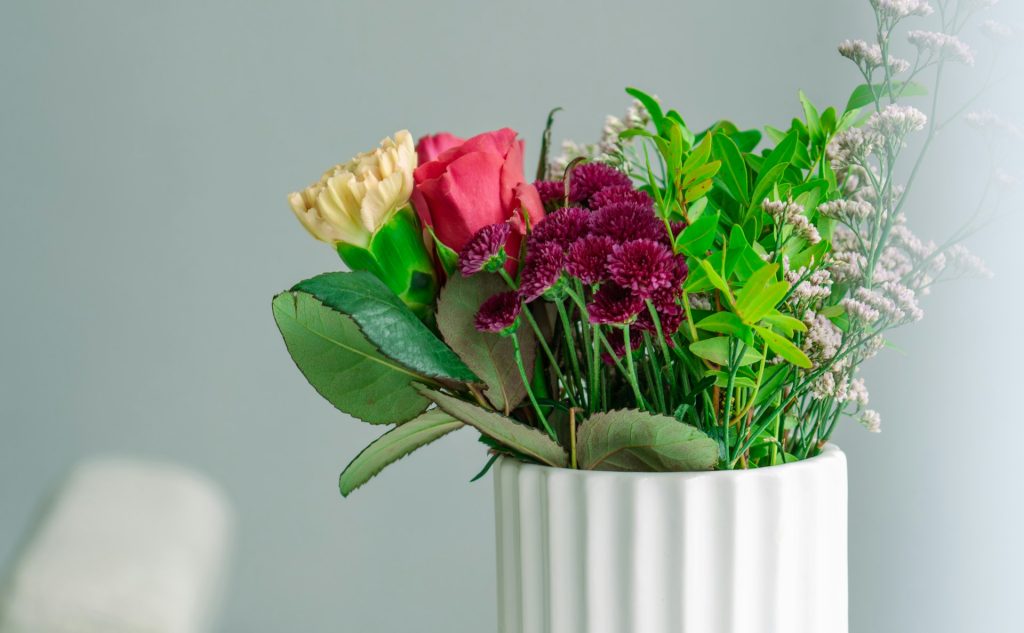 A colourful bouquet of dried flowers in a white vase.