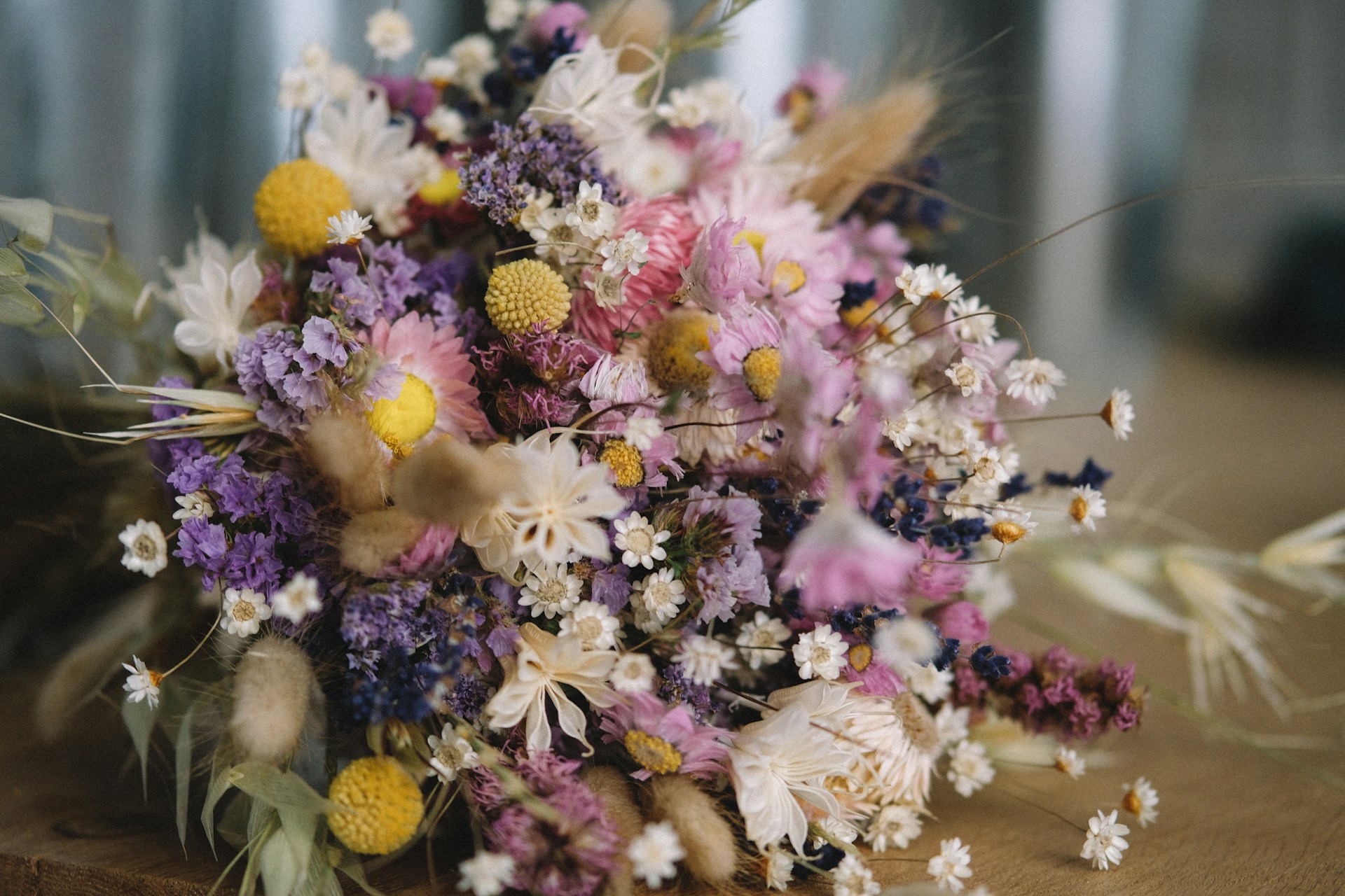 A colourful dried flower bouquet on a brown wooden table.